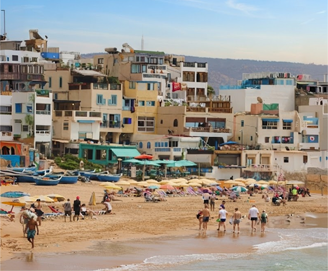 Taghazout beachfront with colourful buildings, fishing boats and people along the shore.