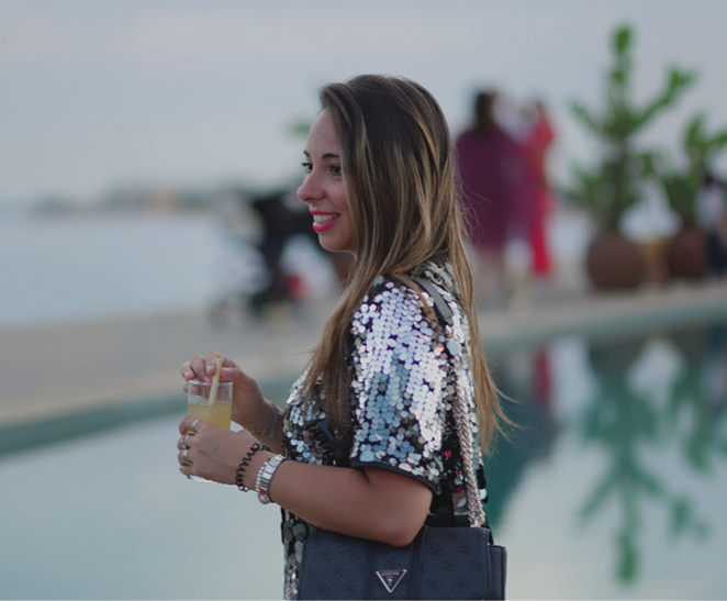 Nu Skin guest in a sequinned outfit enjoying a drink beside the pool.