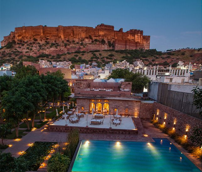 Hotel in India at night with pool and castle behind 