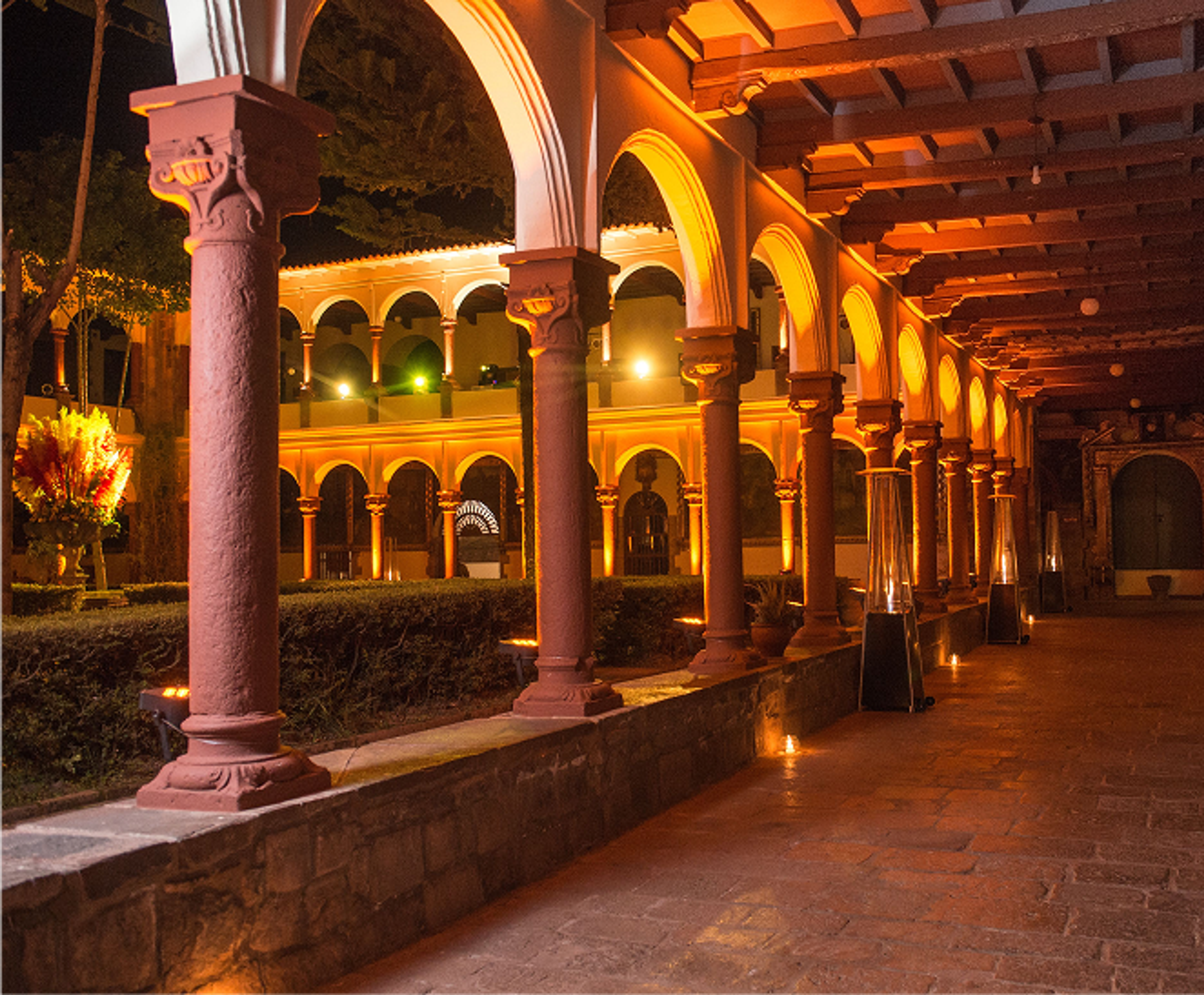 Historic courtyard arches illuminated in warm amber light, with candles lining the walkway.