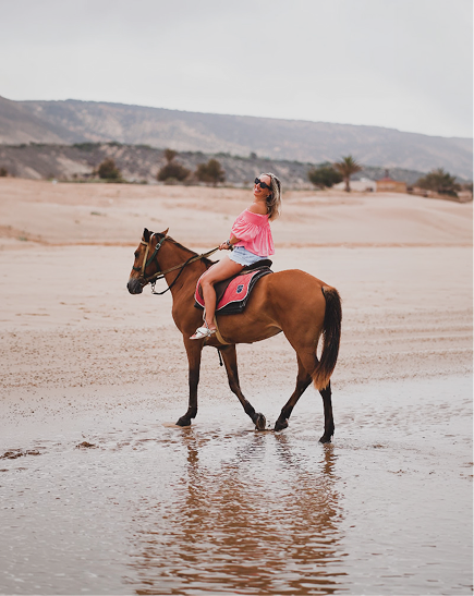 Nu Skin guest riding a horse along the beach in Morocco.