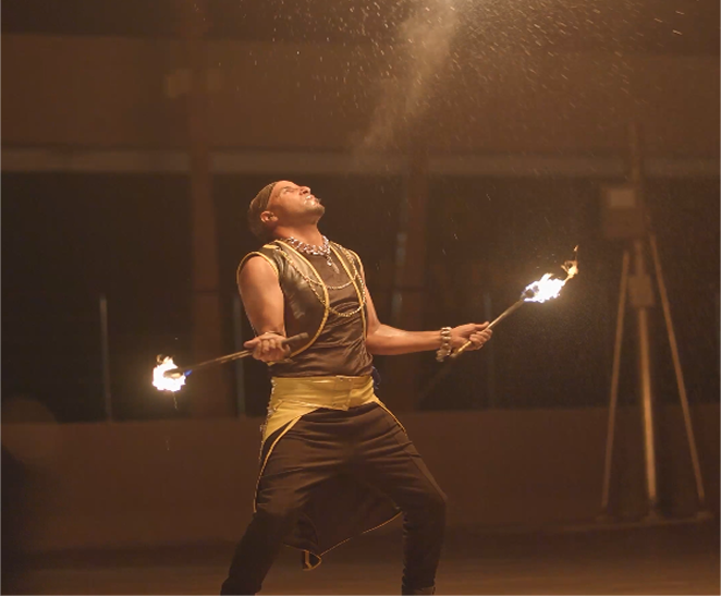 Fire performer holding two flaming torches during the evening entertainment.