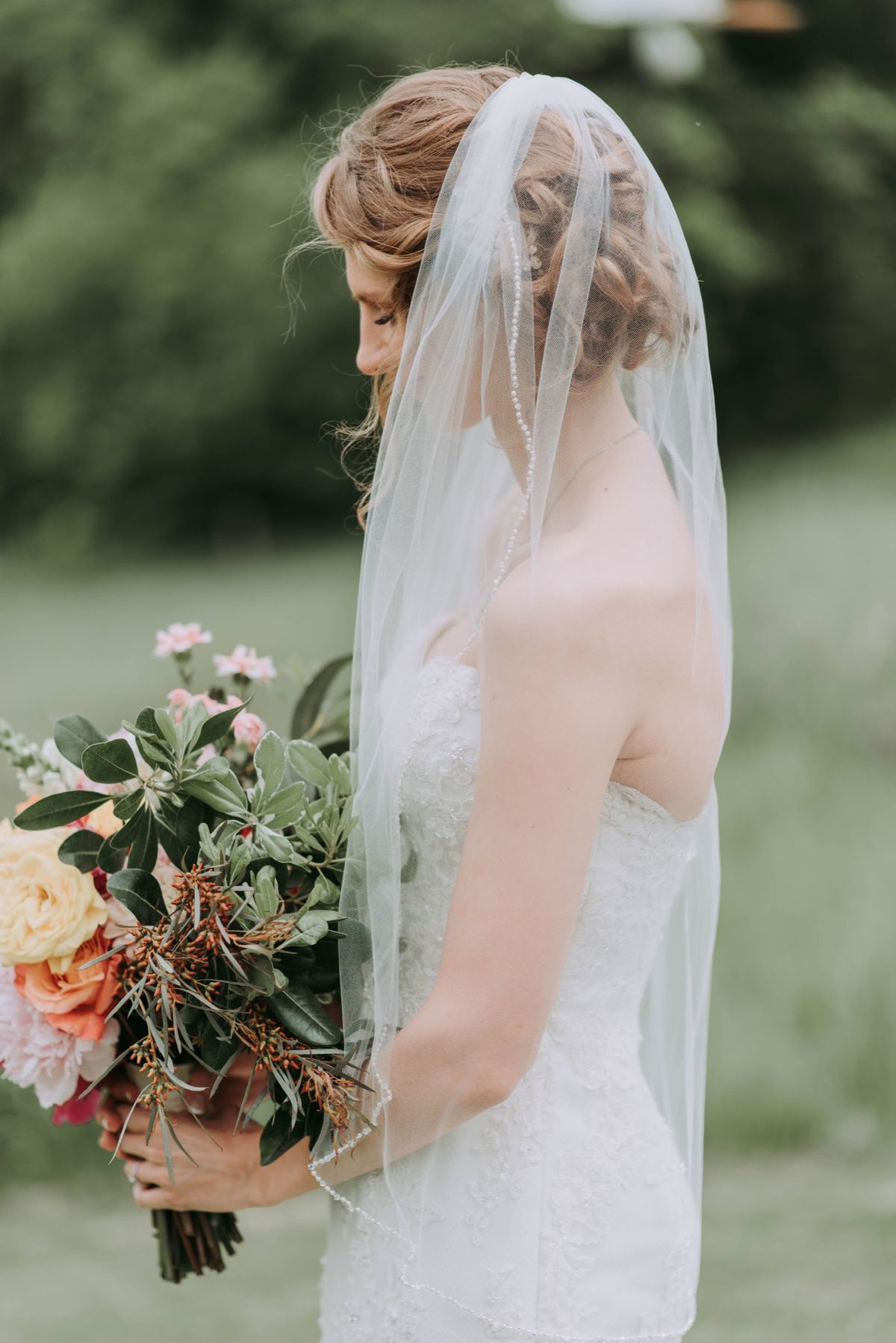 Bride in a long veil holding a garden bouquet