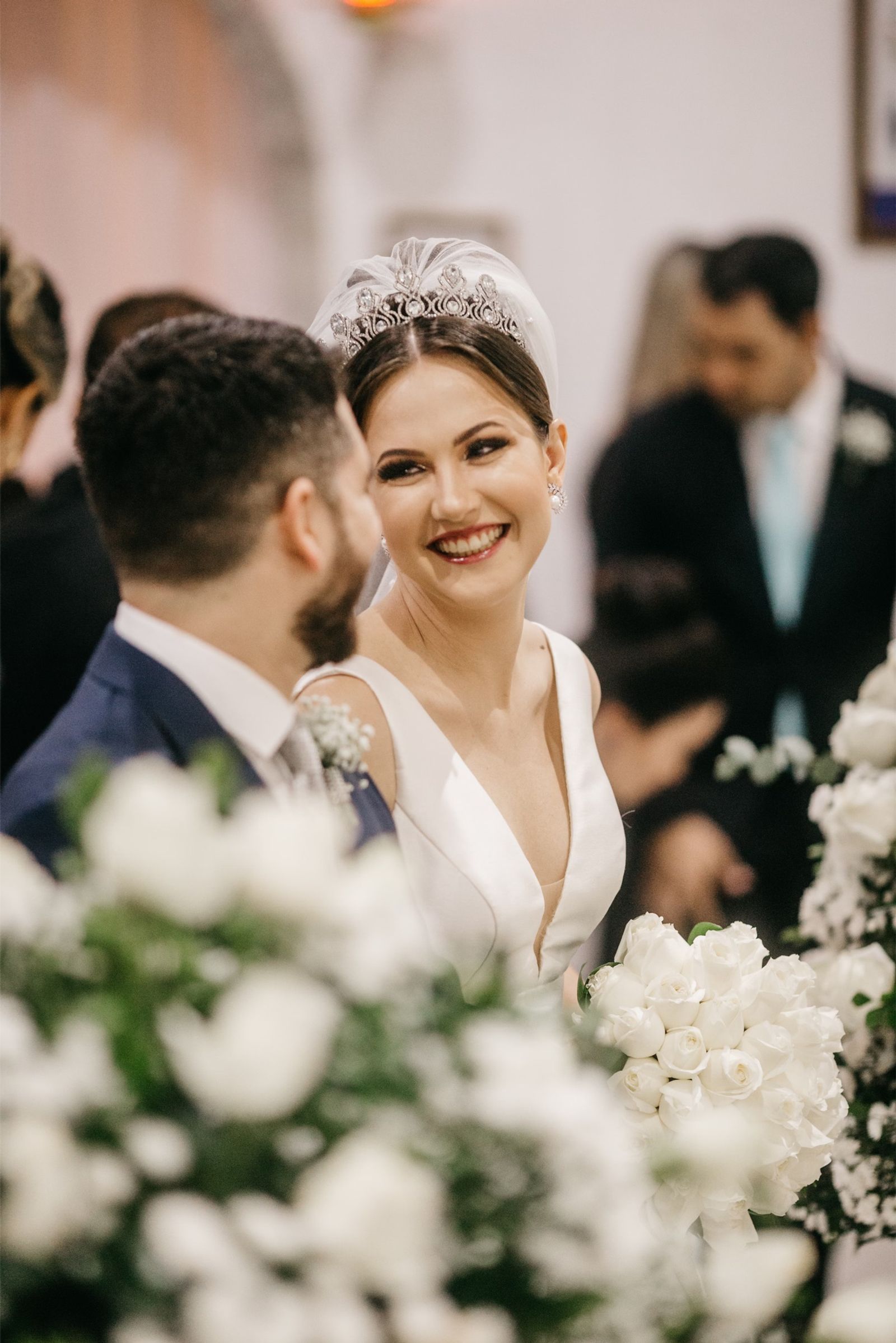 Bride and groom smiling behind white flowers