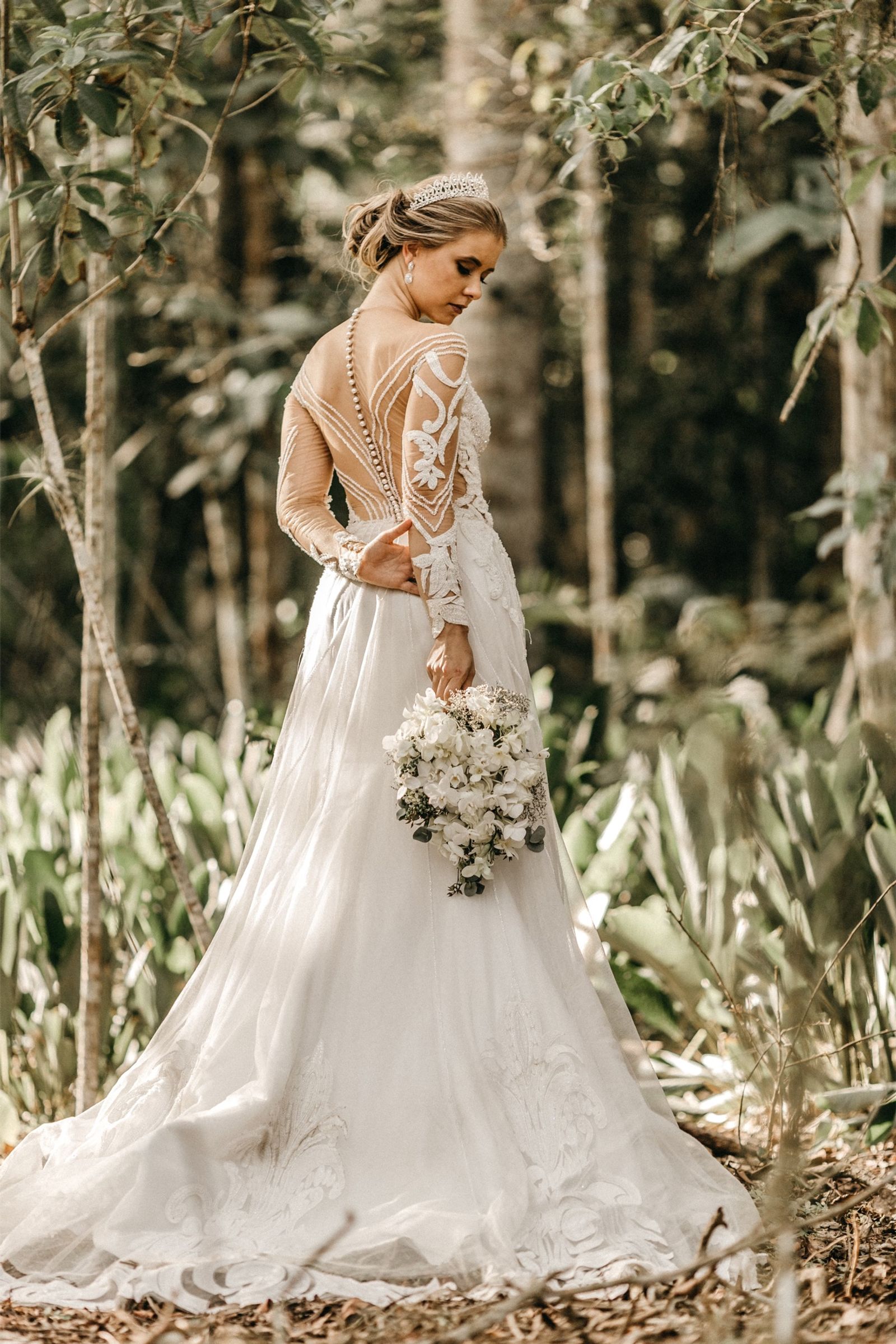 Bride in an open-back lace gown among the trees