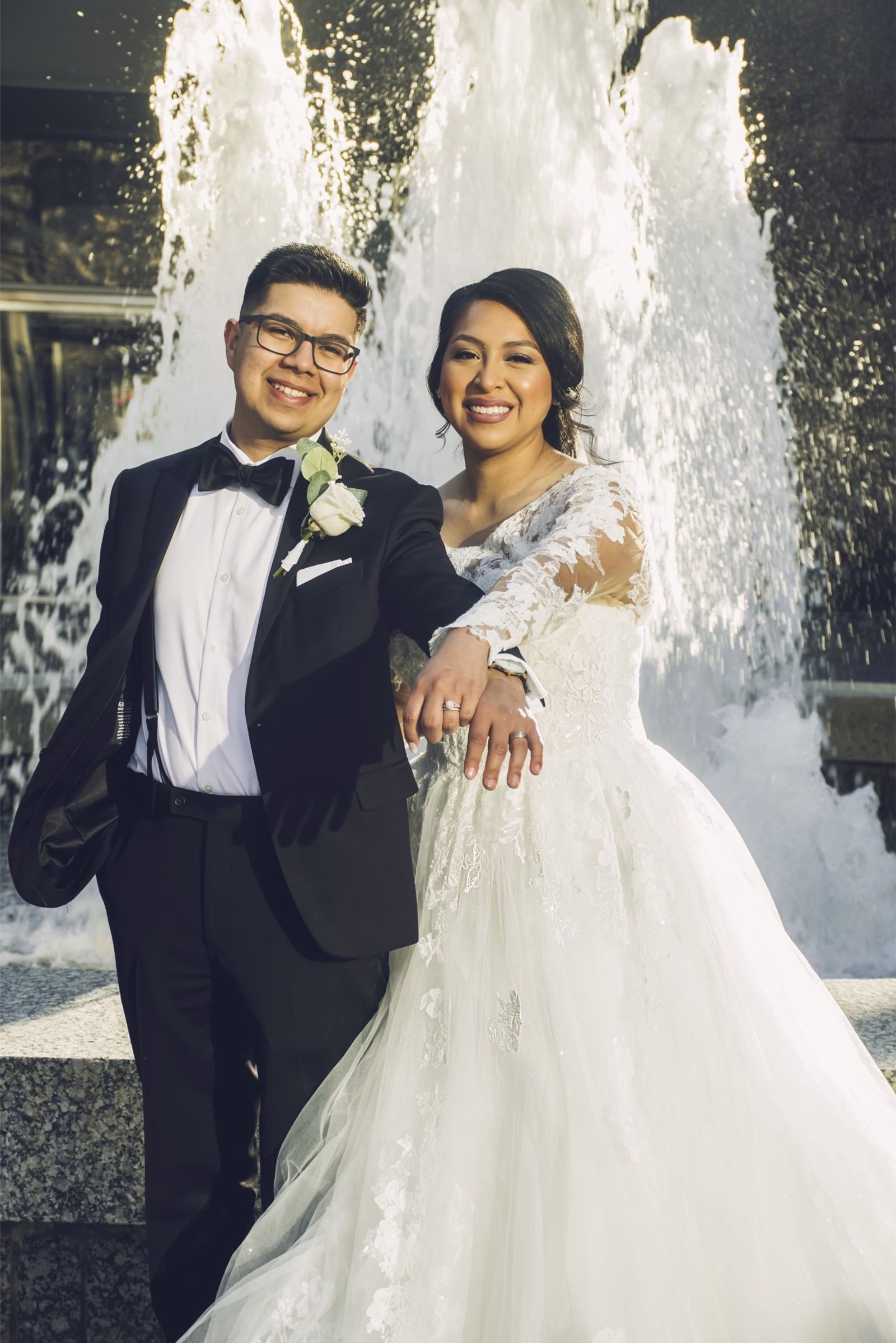 Bride and groom laughing in front of a fountain