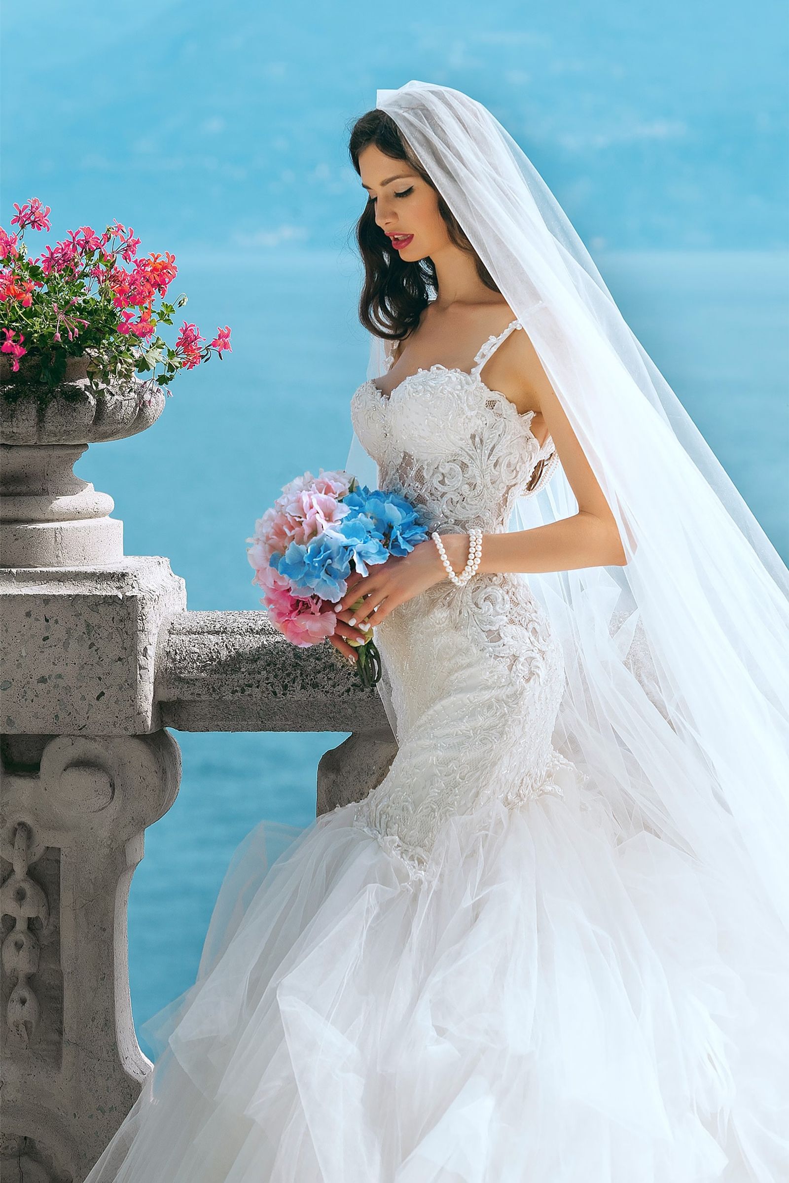 Bride in a flowing gown on a seaside terrace