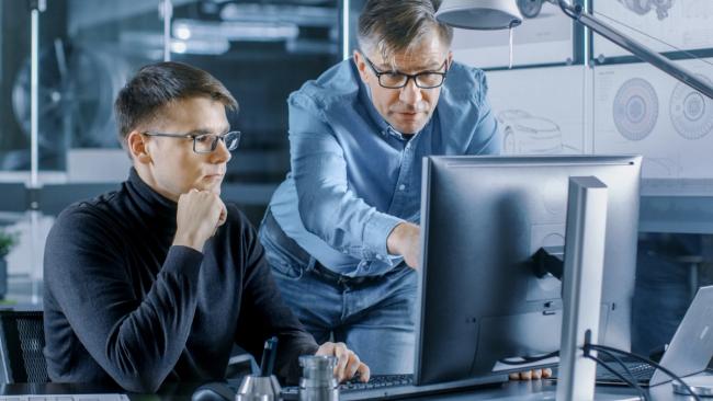A data science leader works with a younger colleague