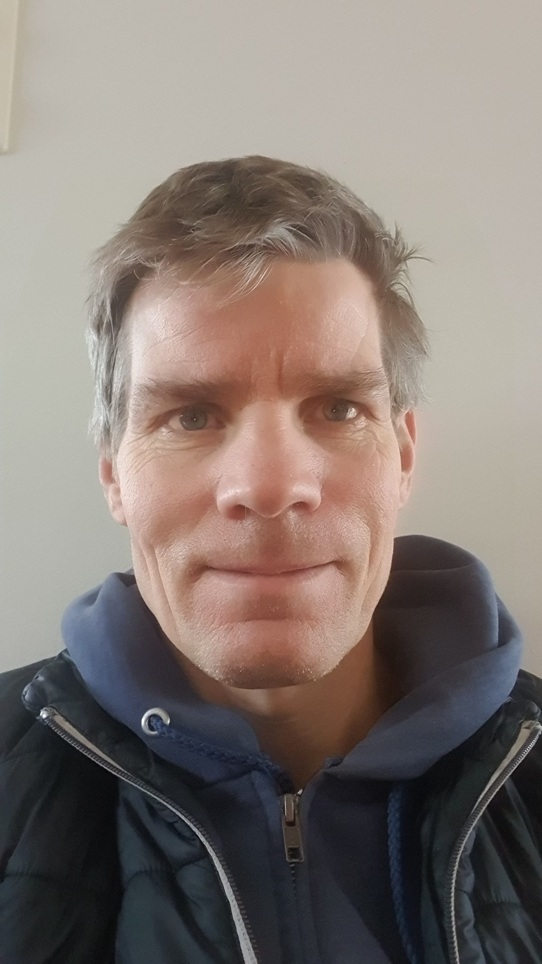 a man wearing a black jacket and a blue hoodie with the letter g on it