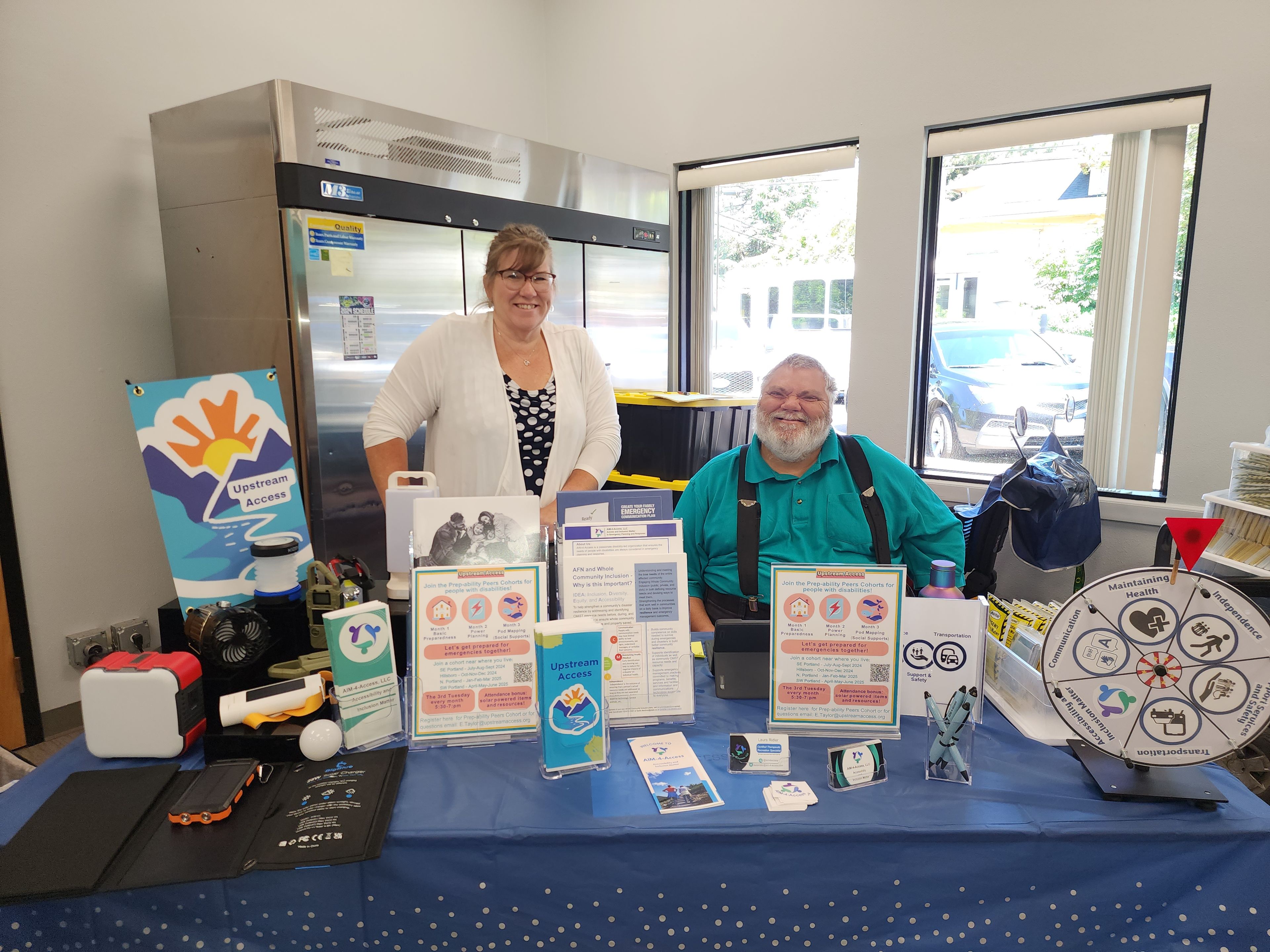 Energized Upstream Access organization members staffing an event booth filled with emergency preparedness resources.