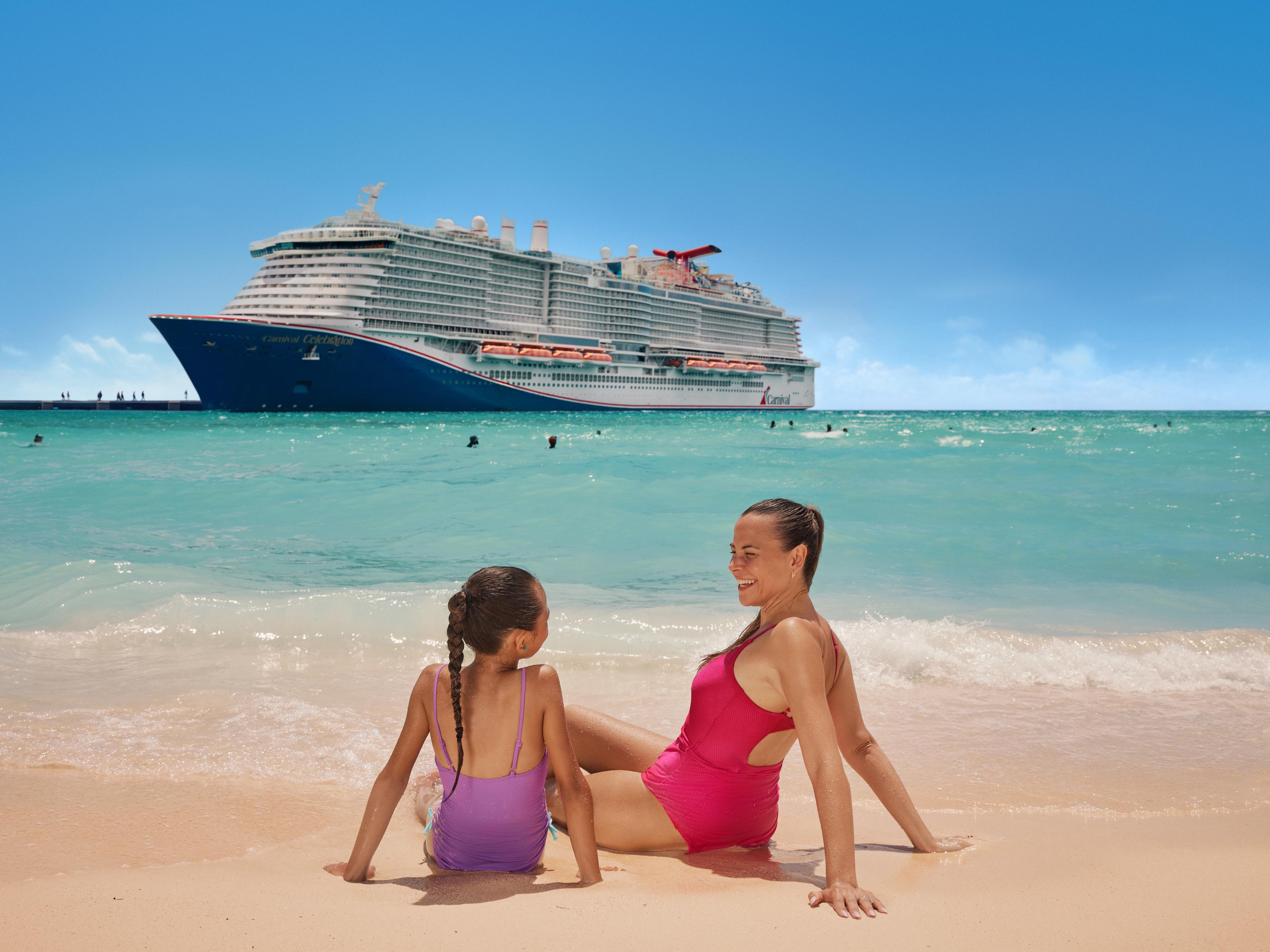Mother and daughter lounging in the sand in front of Carnival cruise ship