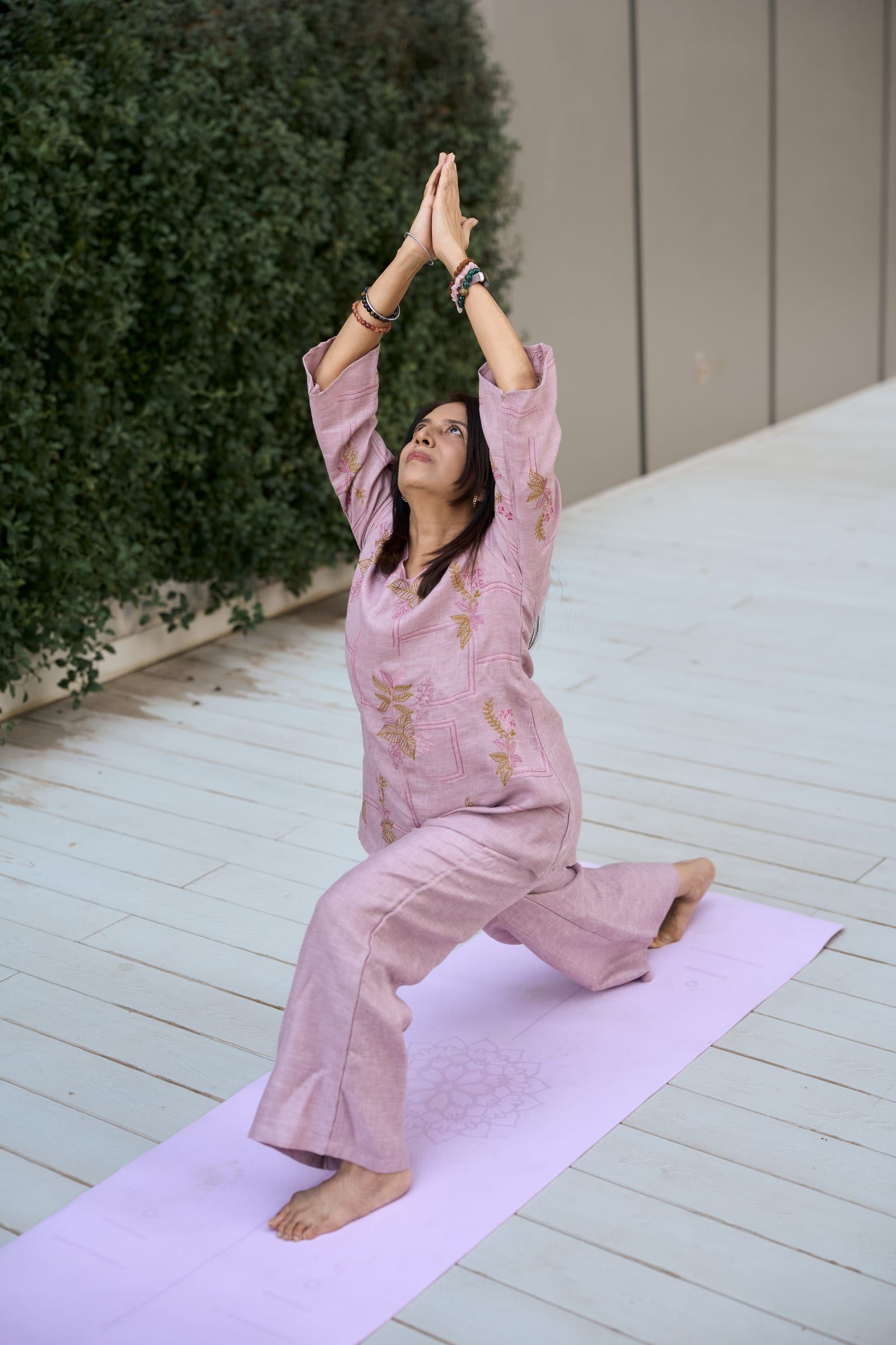Manisha in a low lunge on her mat, arms reaching up