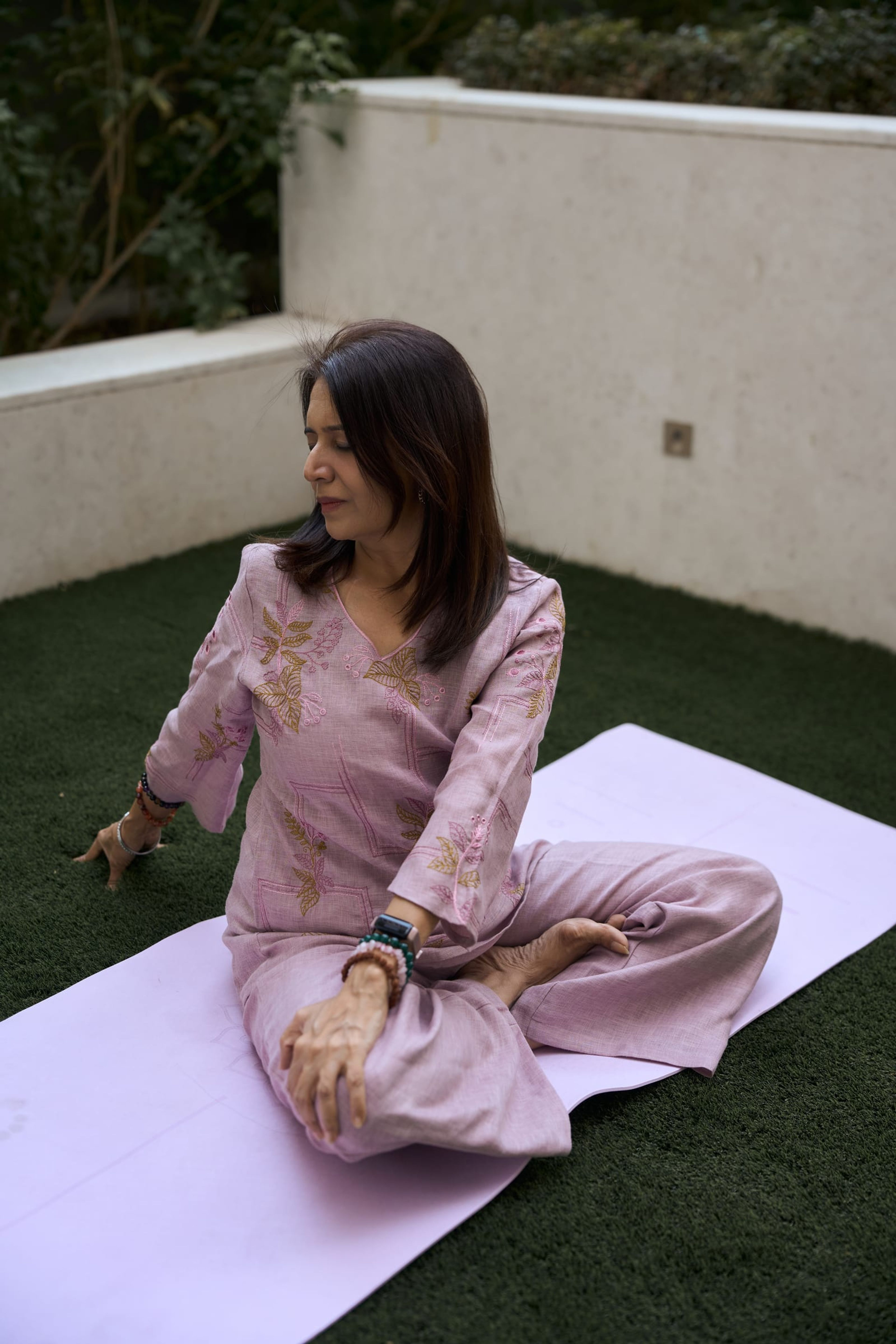 Manisha in a gentle seated twist on her mat outdoors