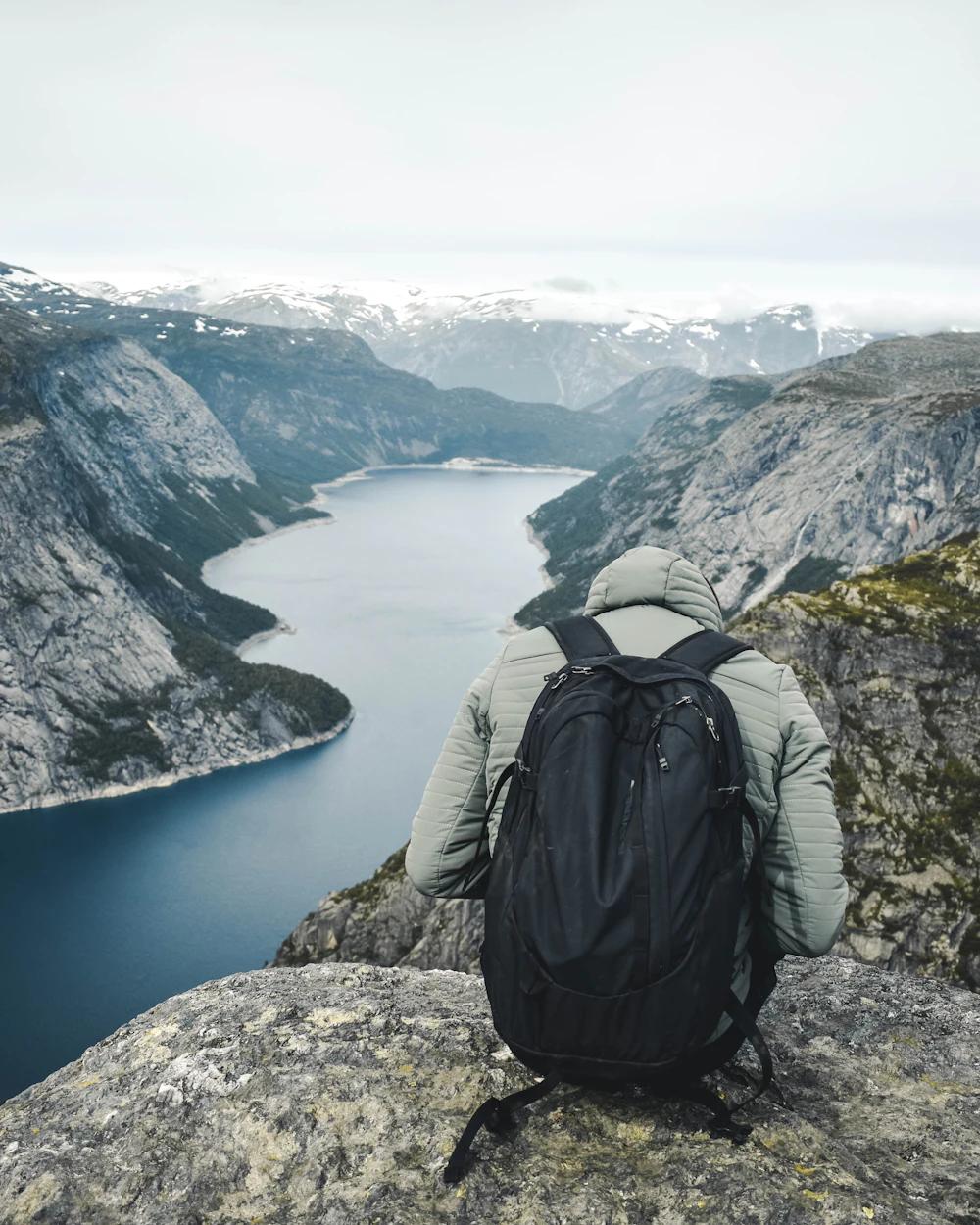 Meg bakfra, sittende på en fjellhylle med sekk, med utsikt over en fjord.
