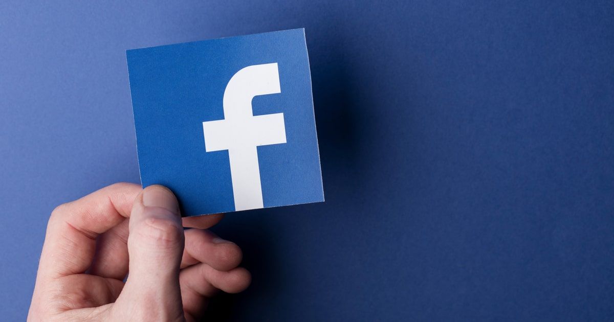 Facebook logo cutout over blue paper