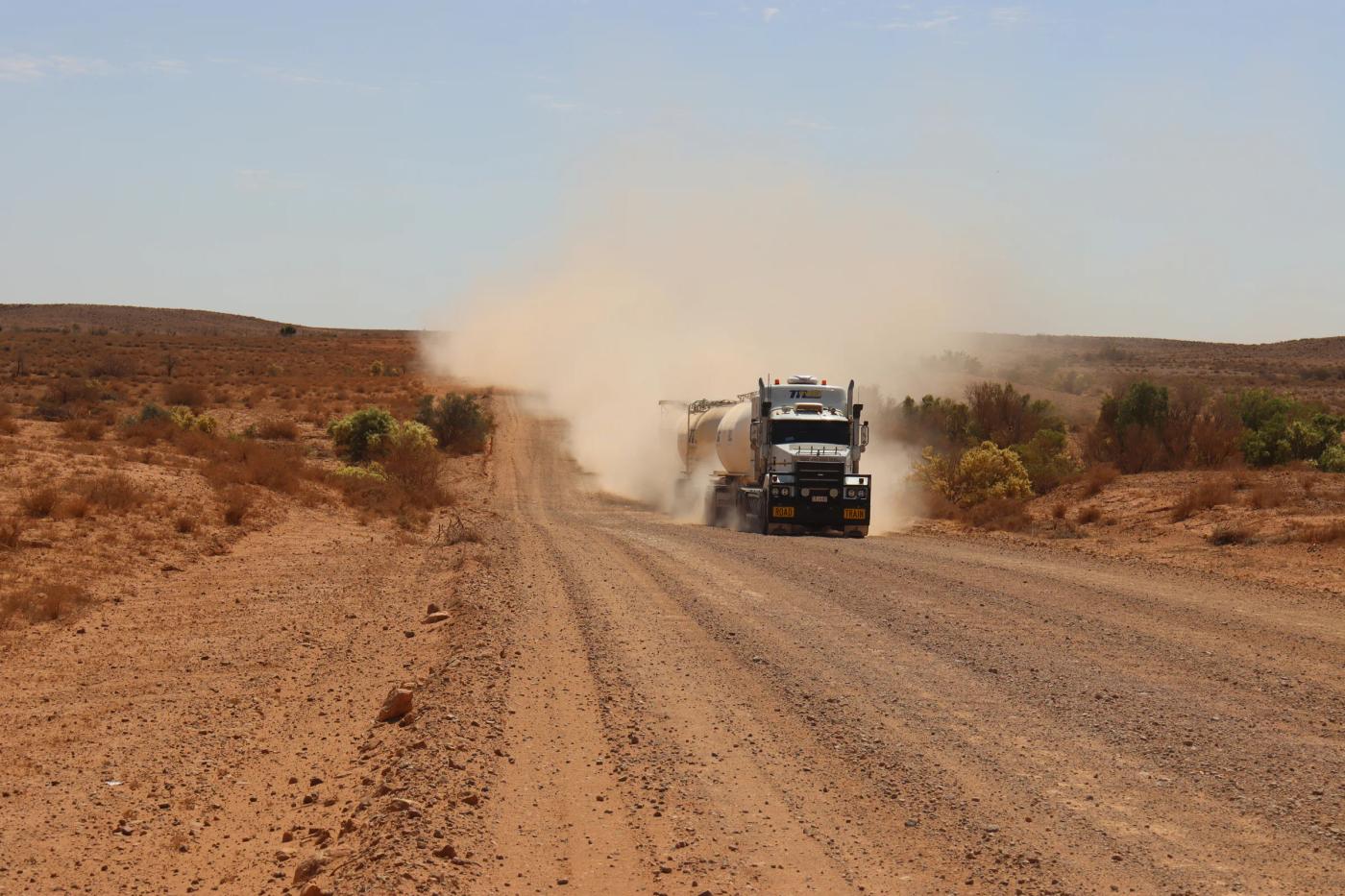 A road train raising dust on an outback dirt road