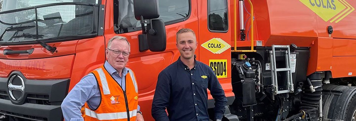 Two people beside a Colas street sweeper