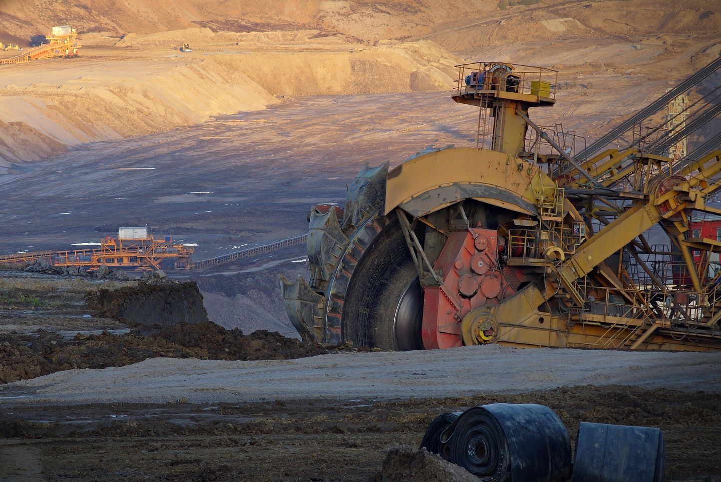 A bucket-wheel excavator at the edge of an open-cut pit, with conveyors on the benches below