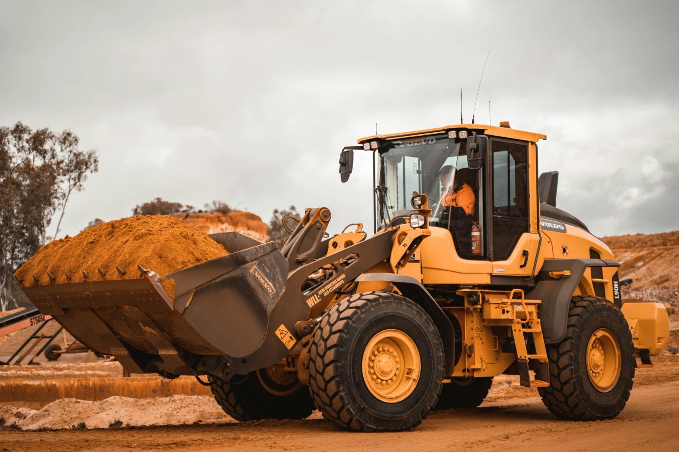 Wheel loader carrying a full bucket of sand across a civil earthworks site