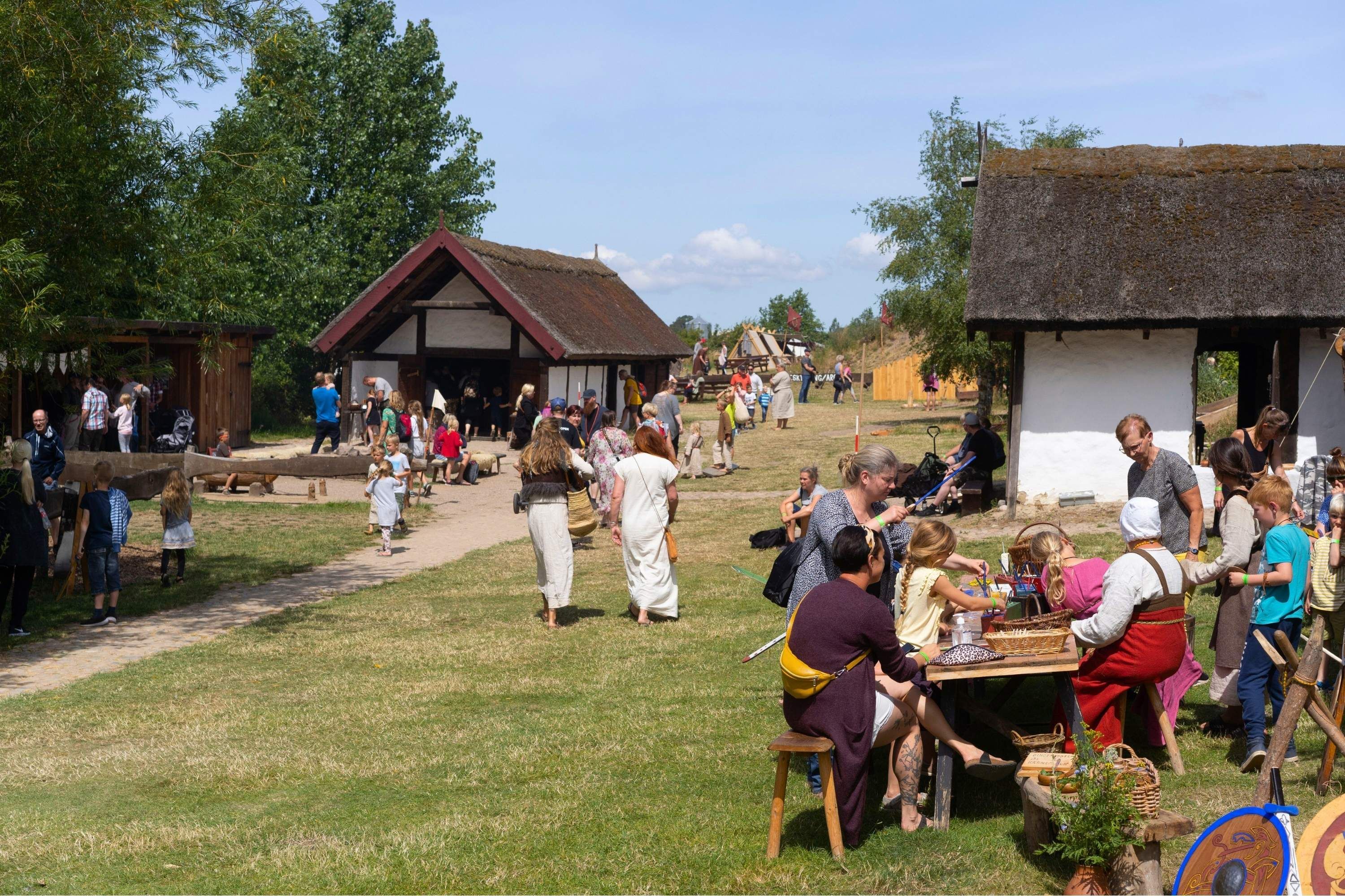 Mennesker i vikingetøj og normalt tøj i aktiviteter i landsbyen