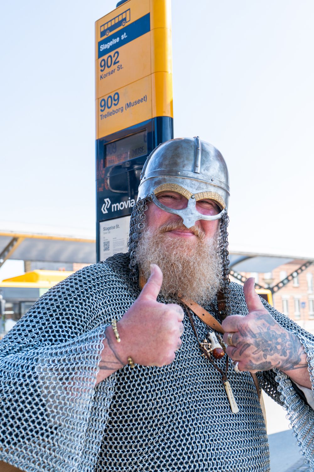 Mand i ringbrynje og vikingehjelm giver thumbs up ved busstoppestedet til Trelleborg Museet.