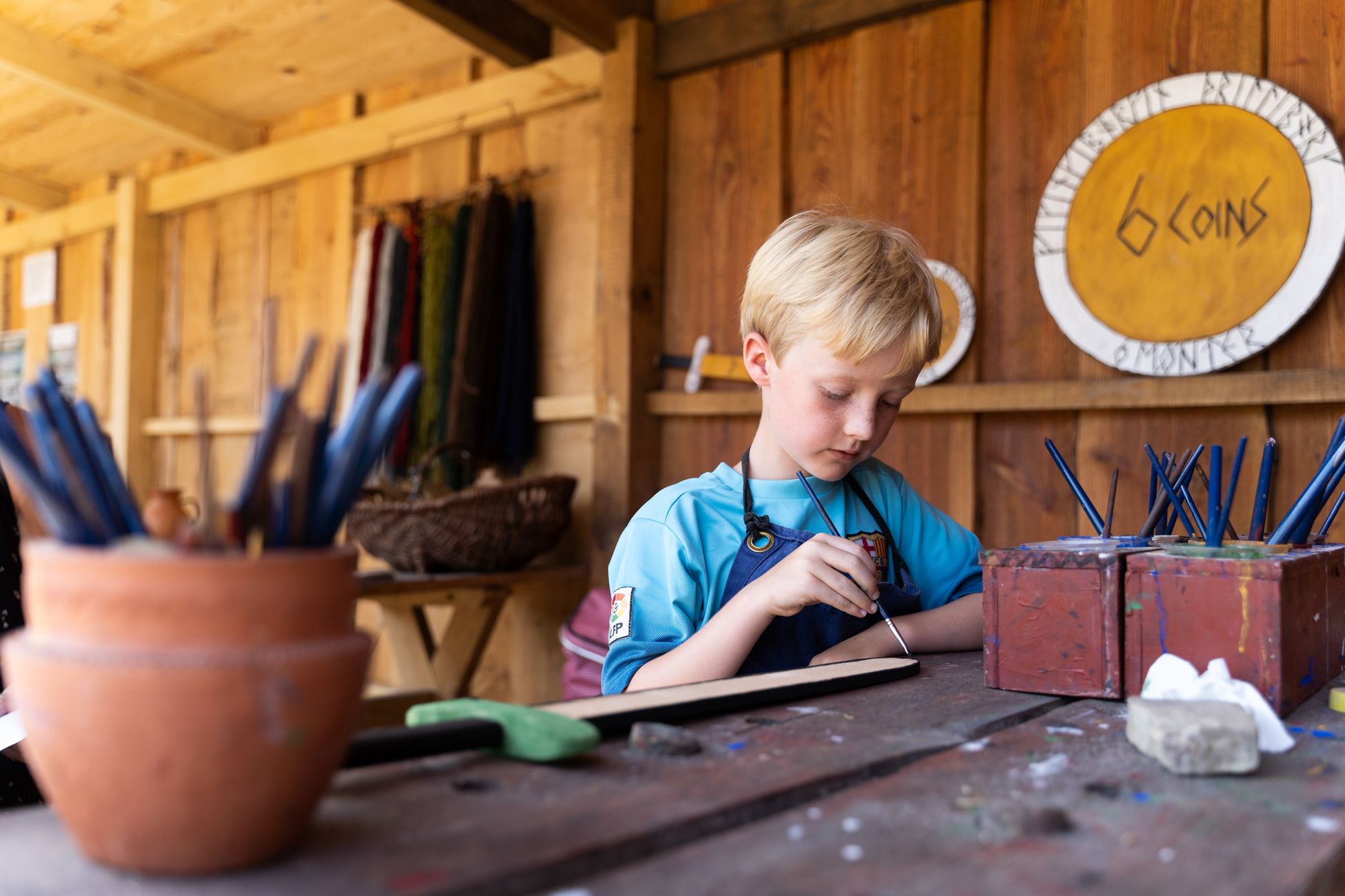Dreng maler koncentreret med vikingernes farver i et vikingeværksted på Trelleborg.