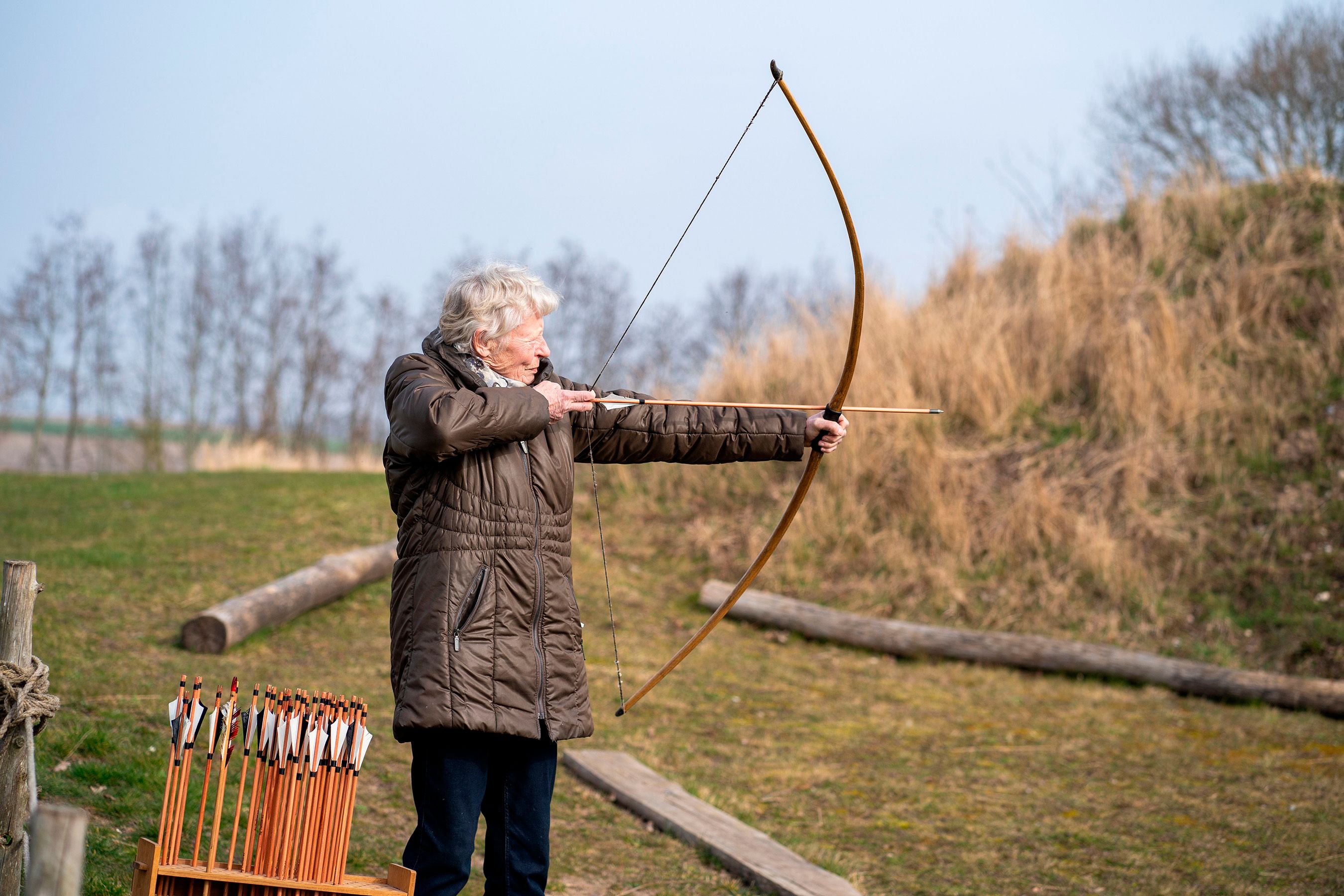Ældre kvinde står med trukket bue