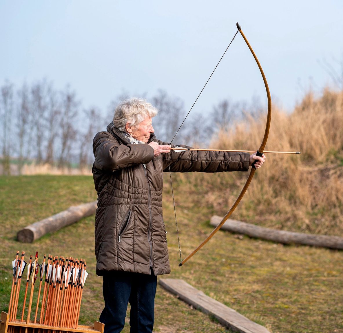 Ældre kvinde står med trukket bue