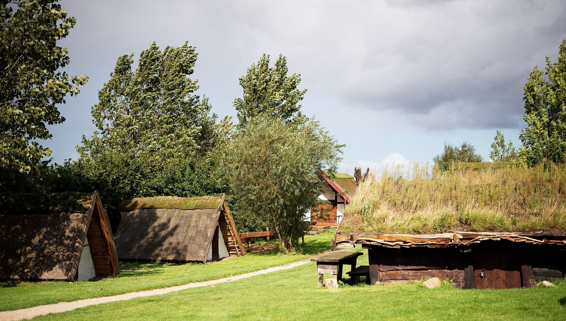 Vikingehuse med trekantet tage ned mod jorden i solen