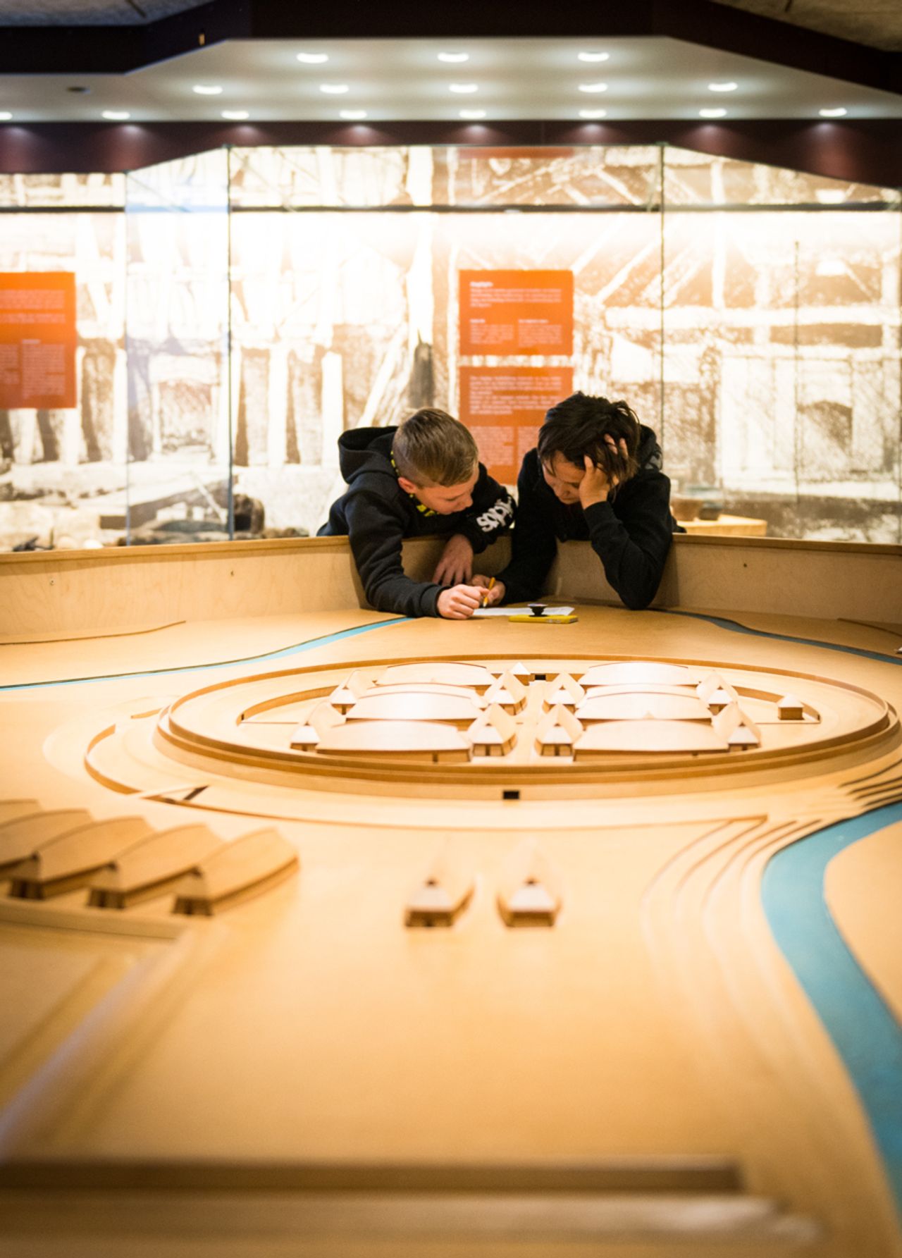 Two boys studying a large wooden scale model of the Trelleborg Viking fortress in the museum exhibition.
