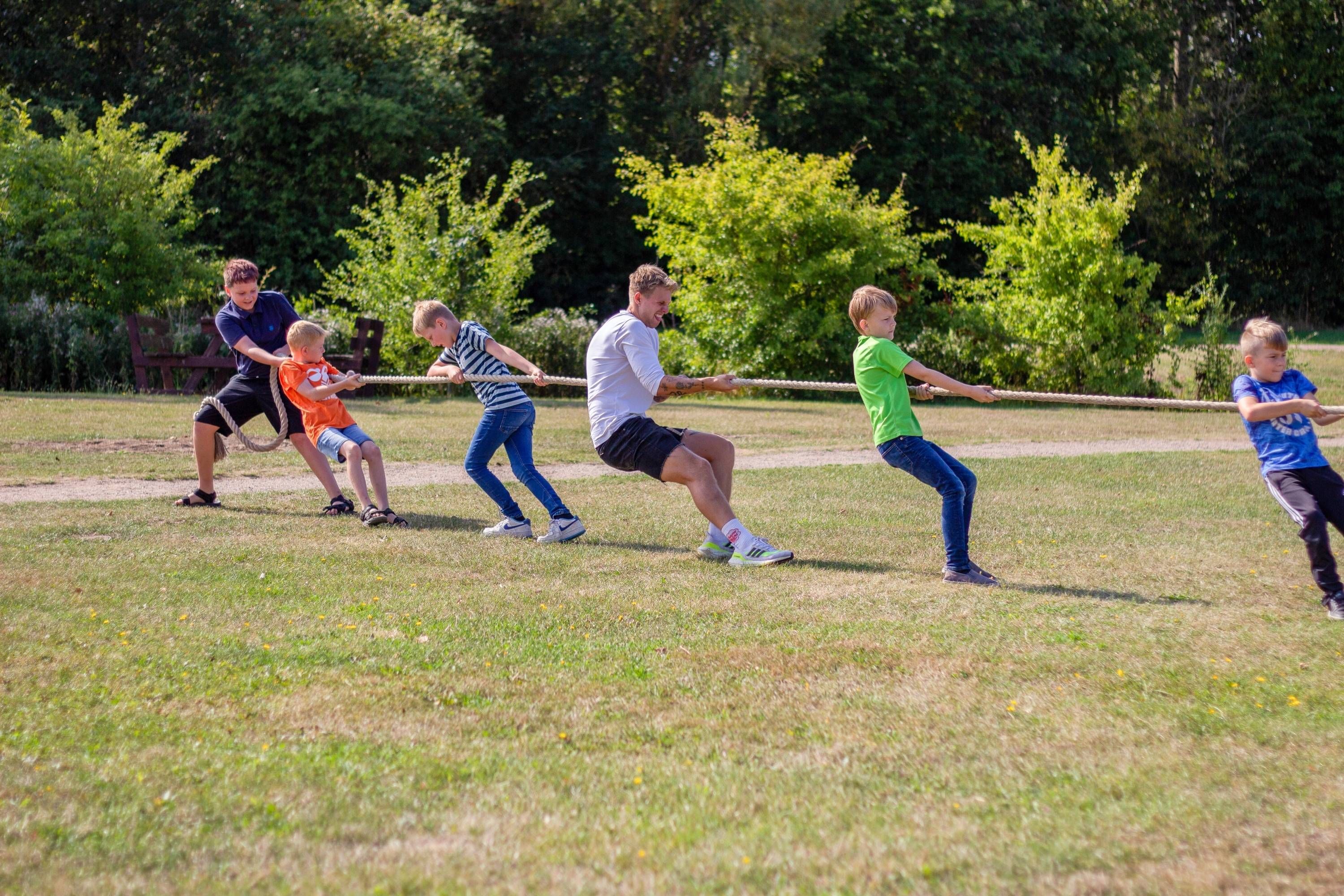 Fem børn og en mand trækker i et tov i tovtrækning