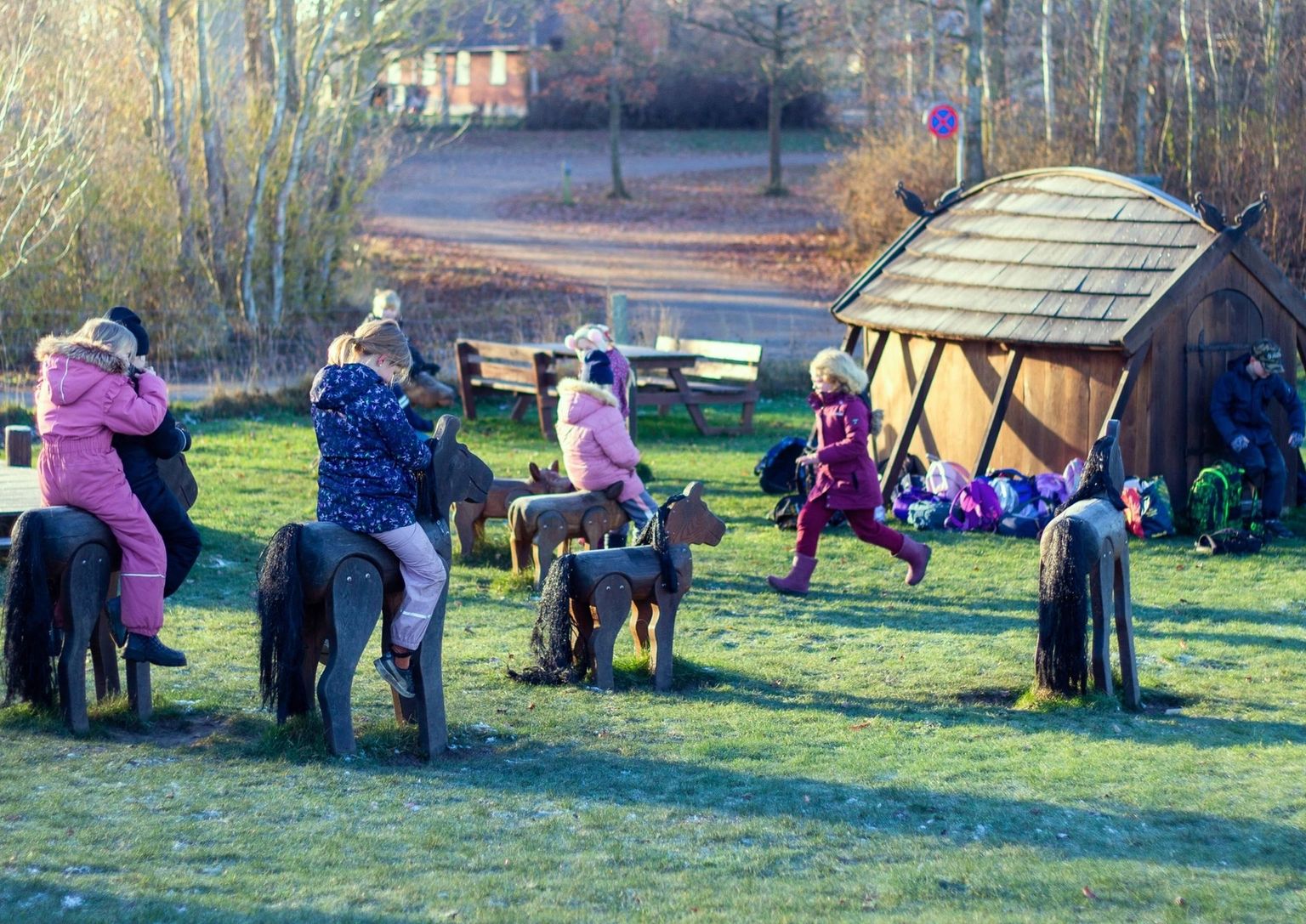 Børn på legepladsen med langhuset i baggrunden