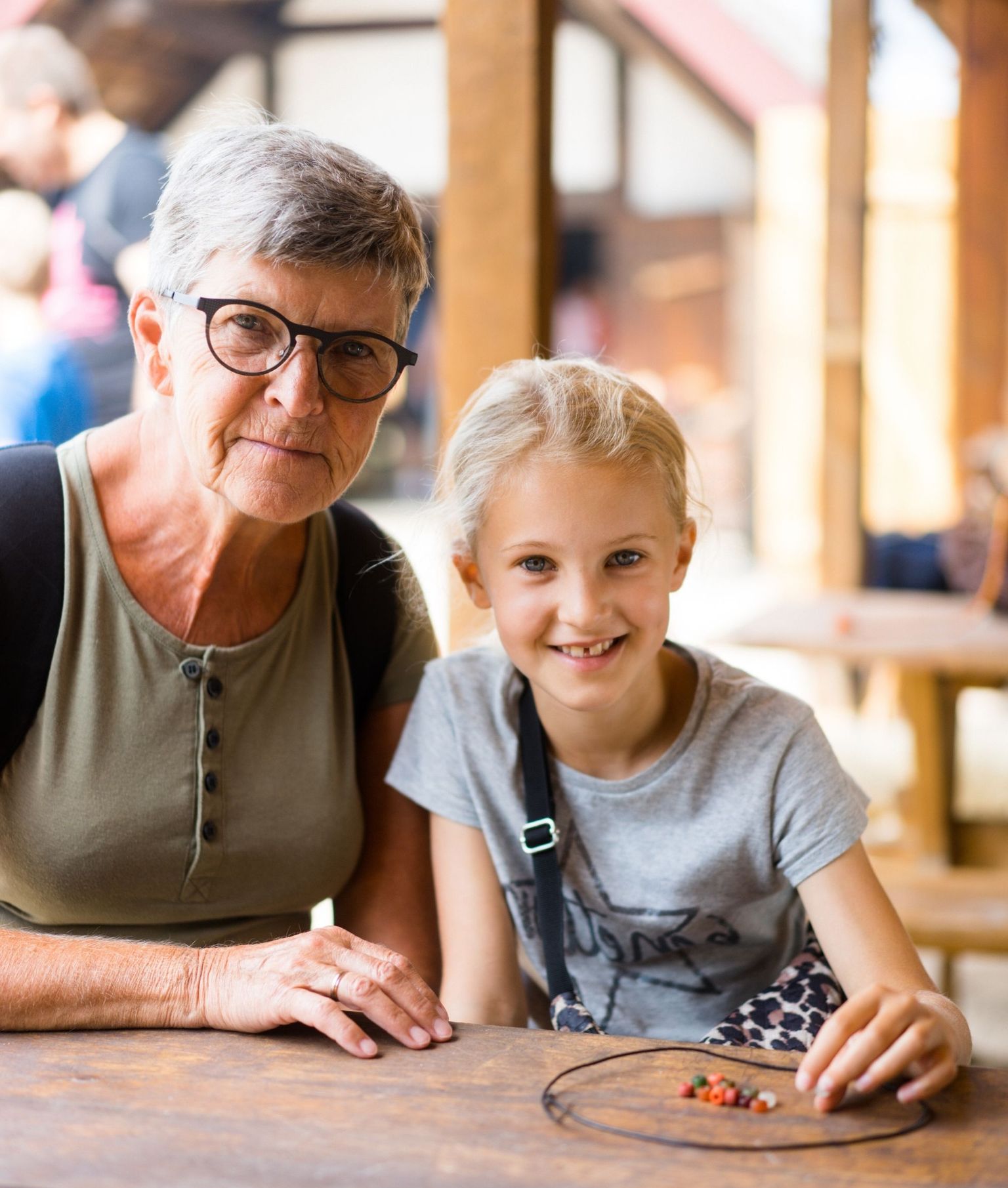 Ældre kvinde og barn sidder sammen om perlesnor