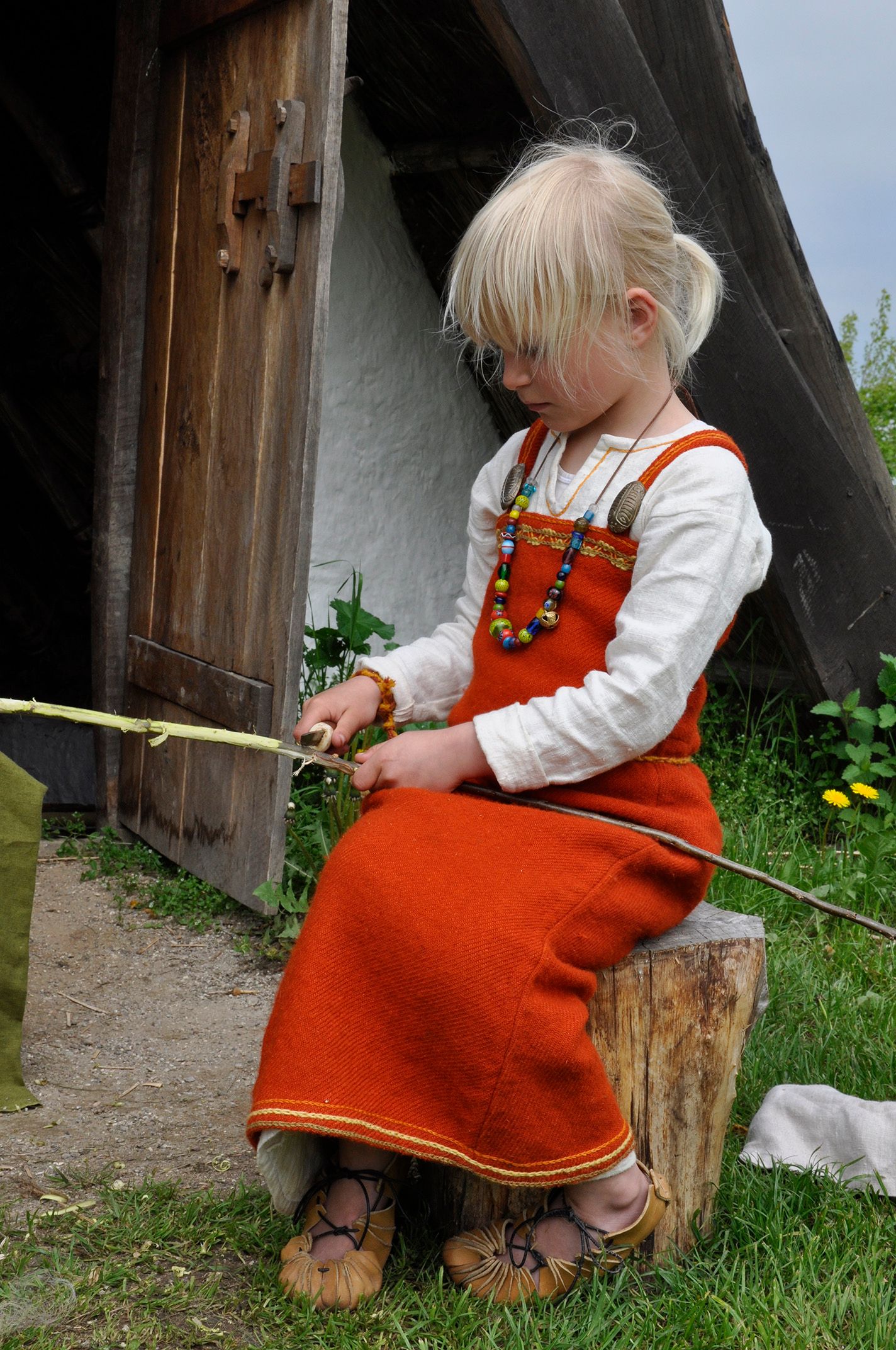 Pige i rød vikingdragt snitter i træ