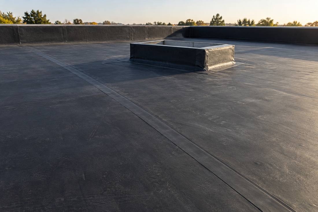 Black EPDM rubber membrane roof with flashing detail around a rooftop curb