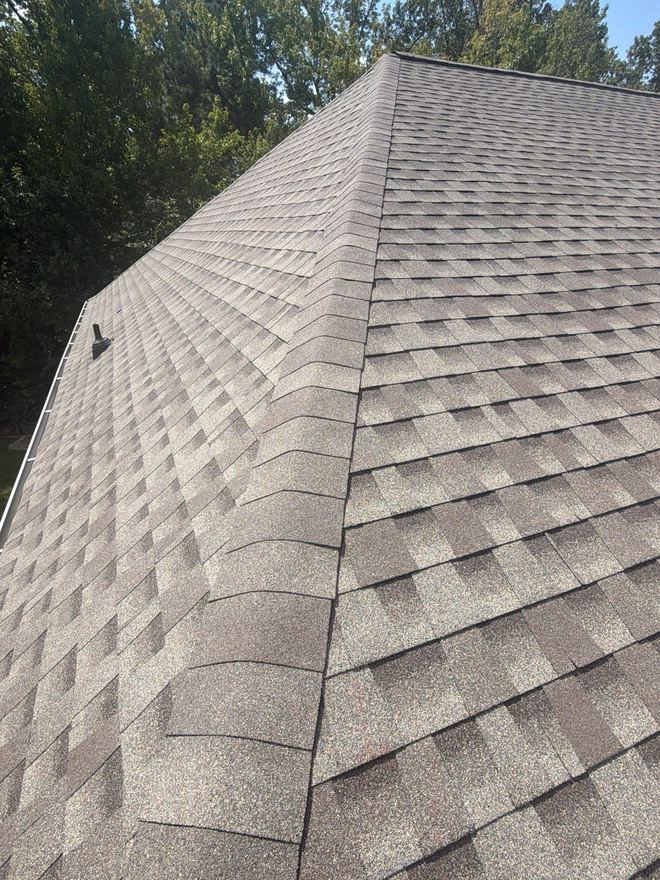 Steep slope of new architectural shingles meeting the ridge