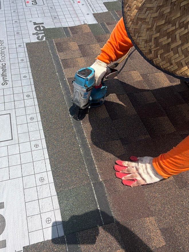 Close-up of a roofer nailing a course of shingles beside the underlayment