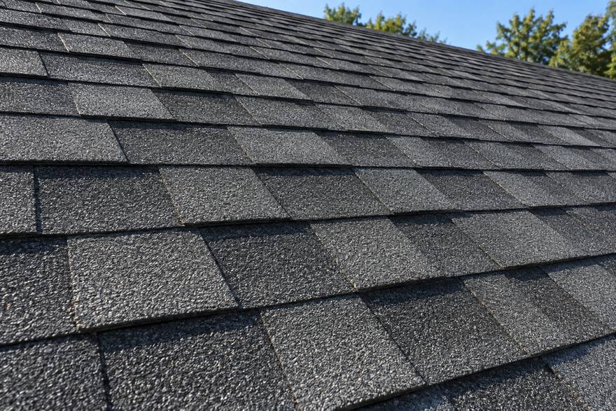 Close view of dark architectural asphalt shingles laid in clean straight courses