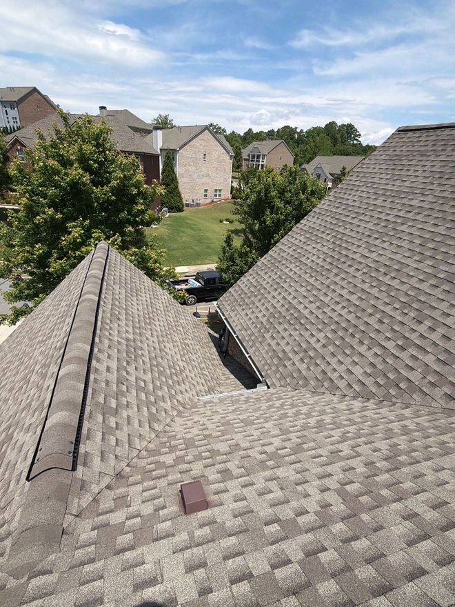 Roof valley between two freshly shingled slopes above a green back lawn