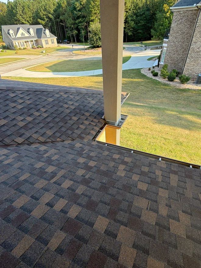 New shingles running to the eave beside a porch column and downspout
