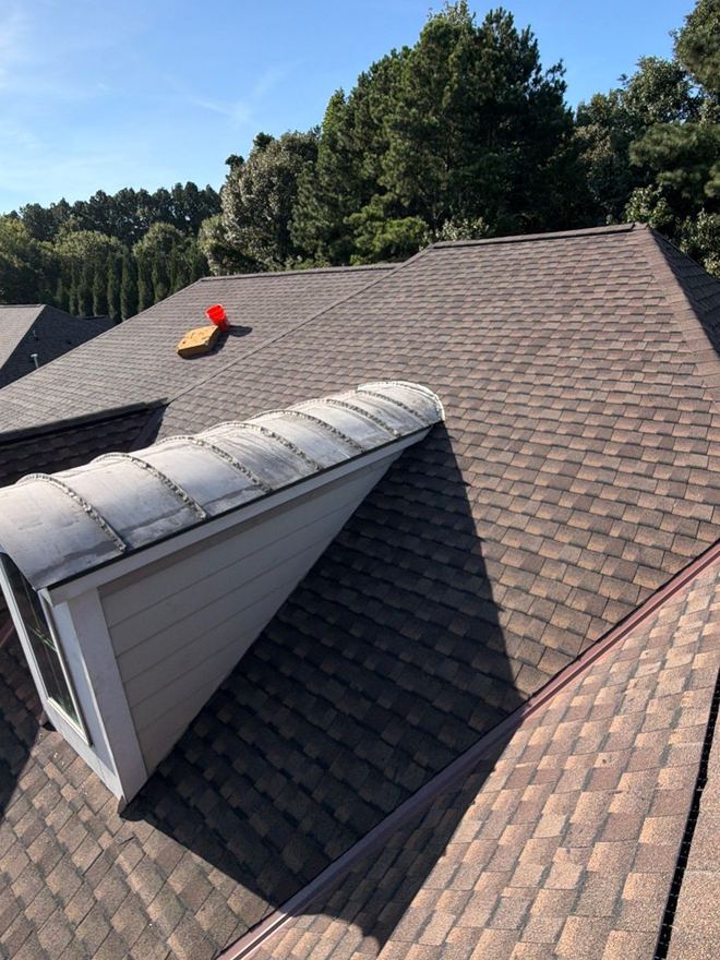 Dormer finished in new shingles and ridge cap against a clear blue sky
