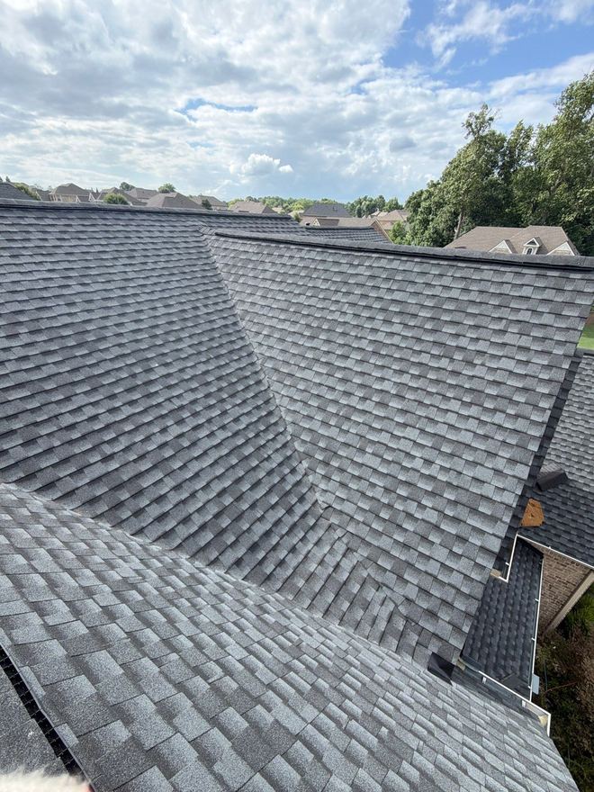 Hip roof in new grey architectural shingles looking out over the treeline