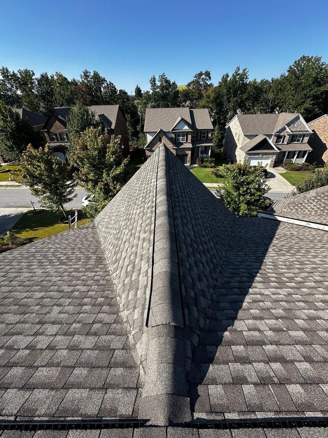 New architectural shingles and ridge cap on a two-storey home, neighbouring houses behind
