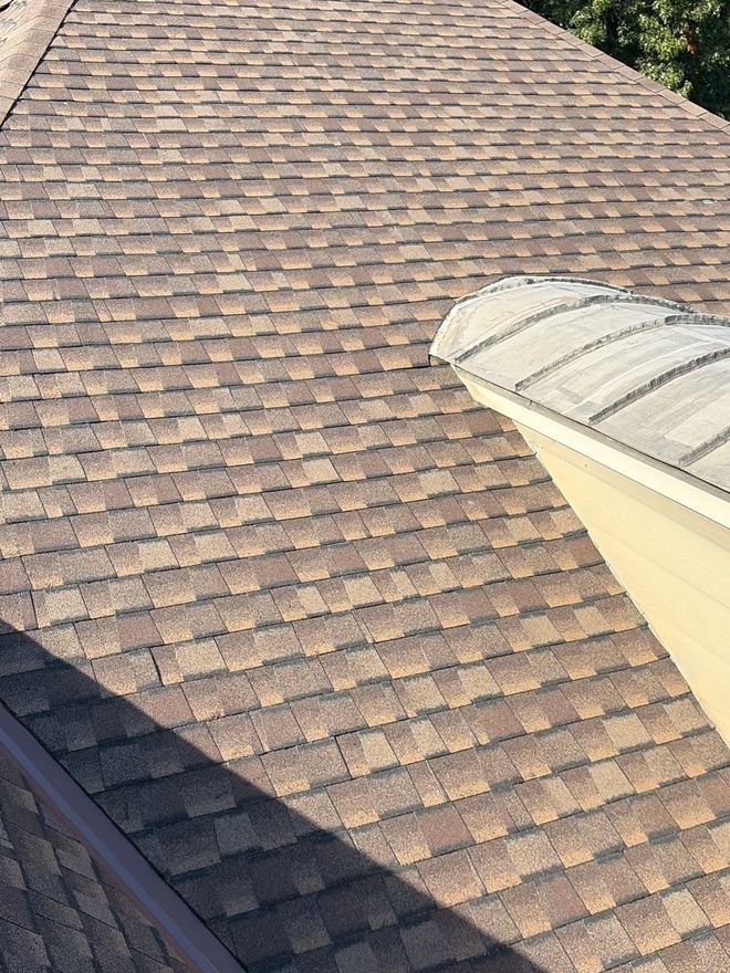 Warm-tone shingles running down to an eyebrow dormer