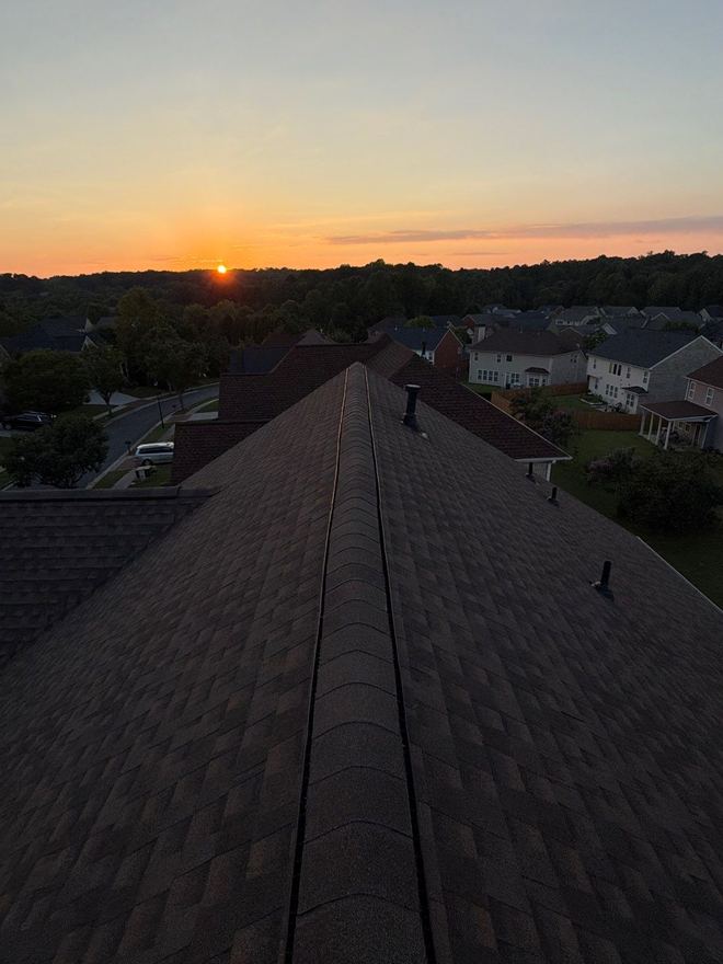 Sunset behind the ridge of a finished roof, subdivision below
