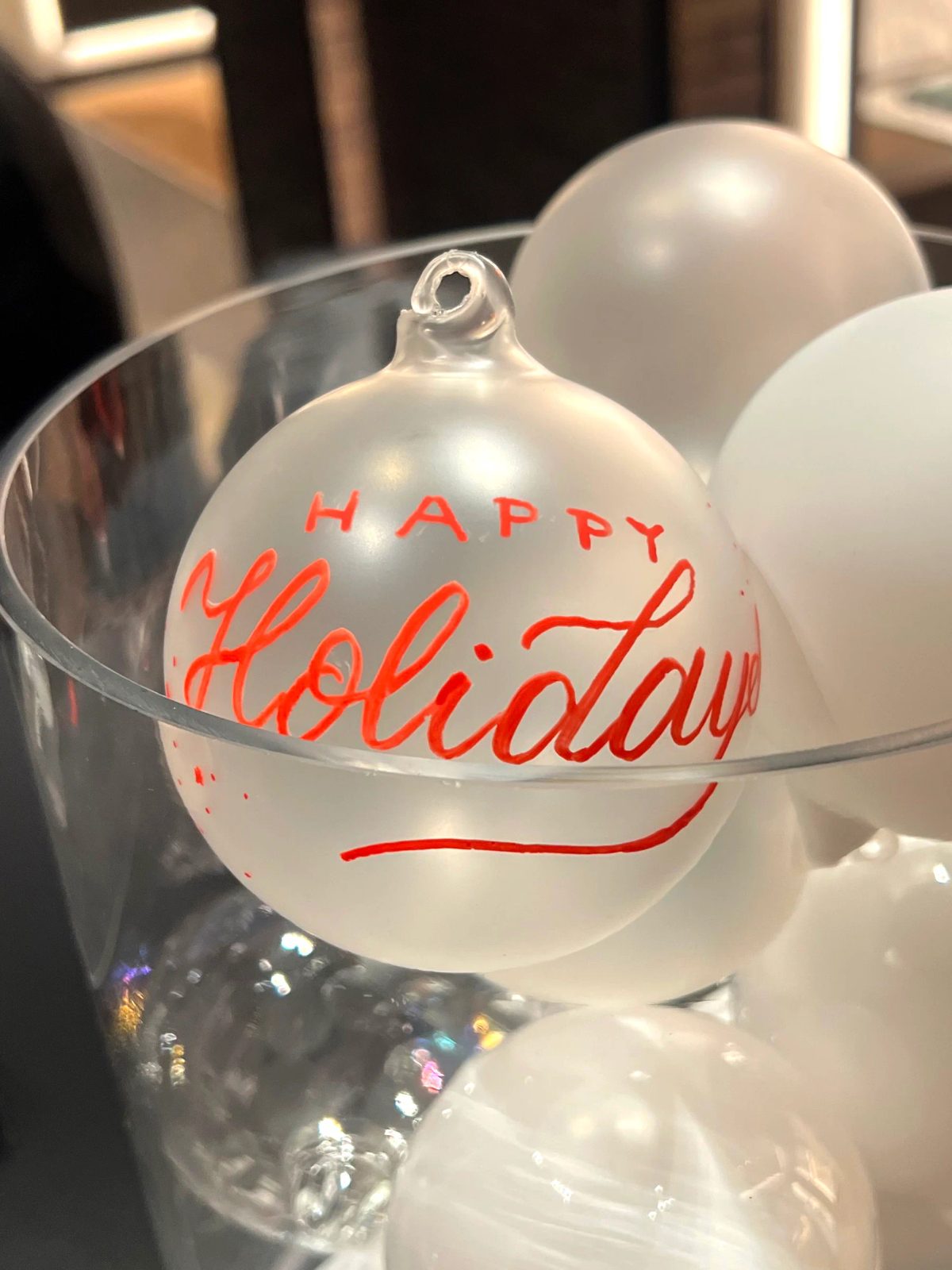 White holiday ornament with red handwritten Happy Holidays lettering