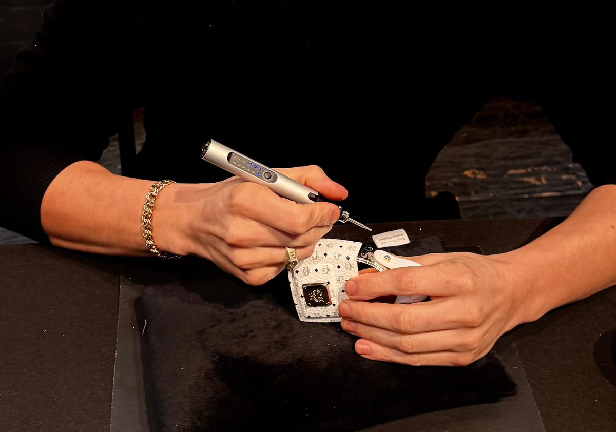 Rodolfo lettering a miniature leather bag at an event