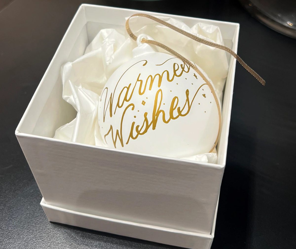 White ornament with gold Warmest Wishes lettering in a gift box