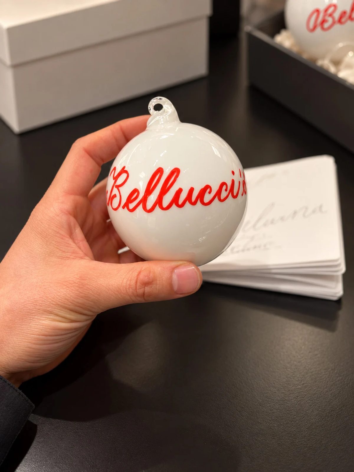 Hand holding a white ornament personalized with red lettering