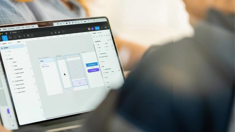Eine Person arbeitet an einem Laptop in Figma an den Komponenten eines digitalen Designsystems.
